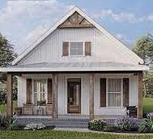 White wooden cottage with a steep gabled roof, front porch, and brown shutters on the windows.