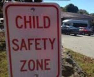 child safety zone images 1 - NARSOL Sign reads 'CHILD SAFETY ZONE' indicating a pedestrian area by the roadside parking lot