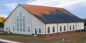 church - NARSOL Exterior of a beige church with tall arched windows and a red-tiled sloped roof under a blue sky